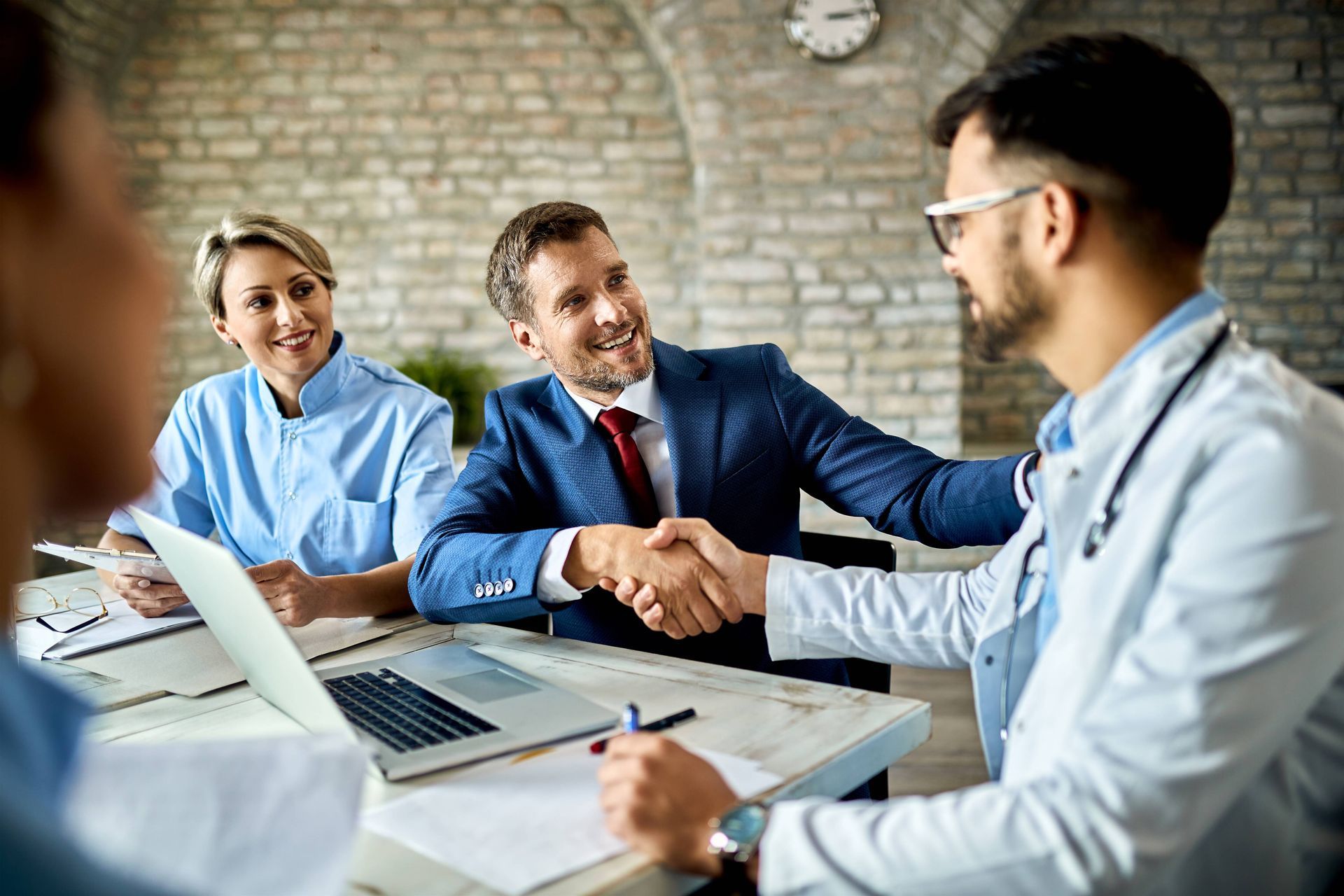 a doctor is shaking hands with a businessman during a meeting