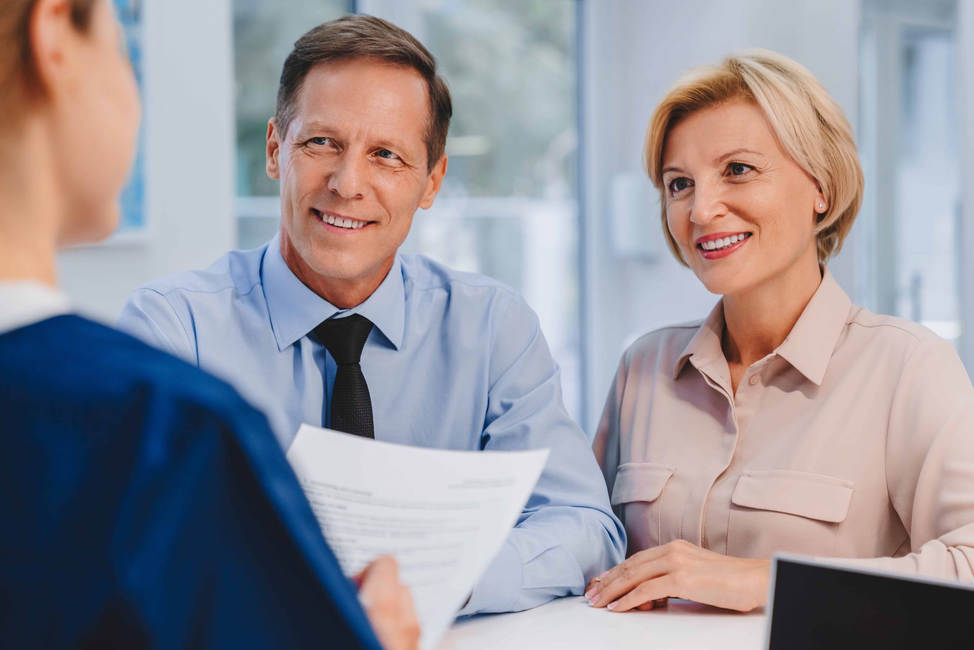 a man and woman are sitting at a table talking to an agent