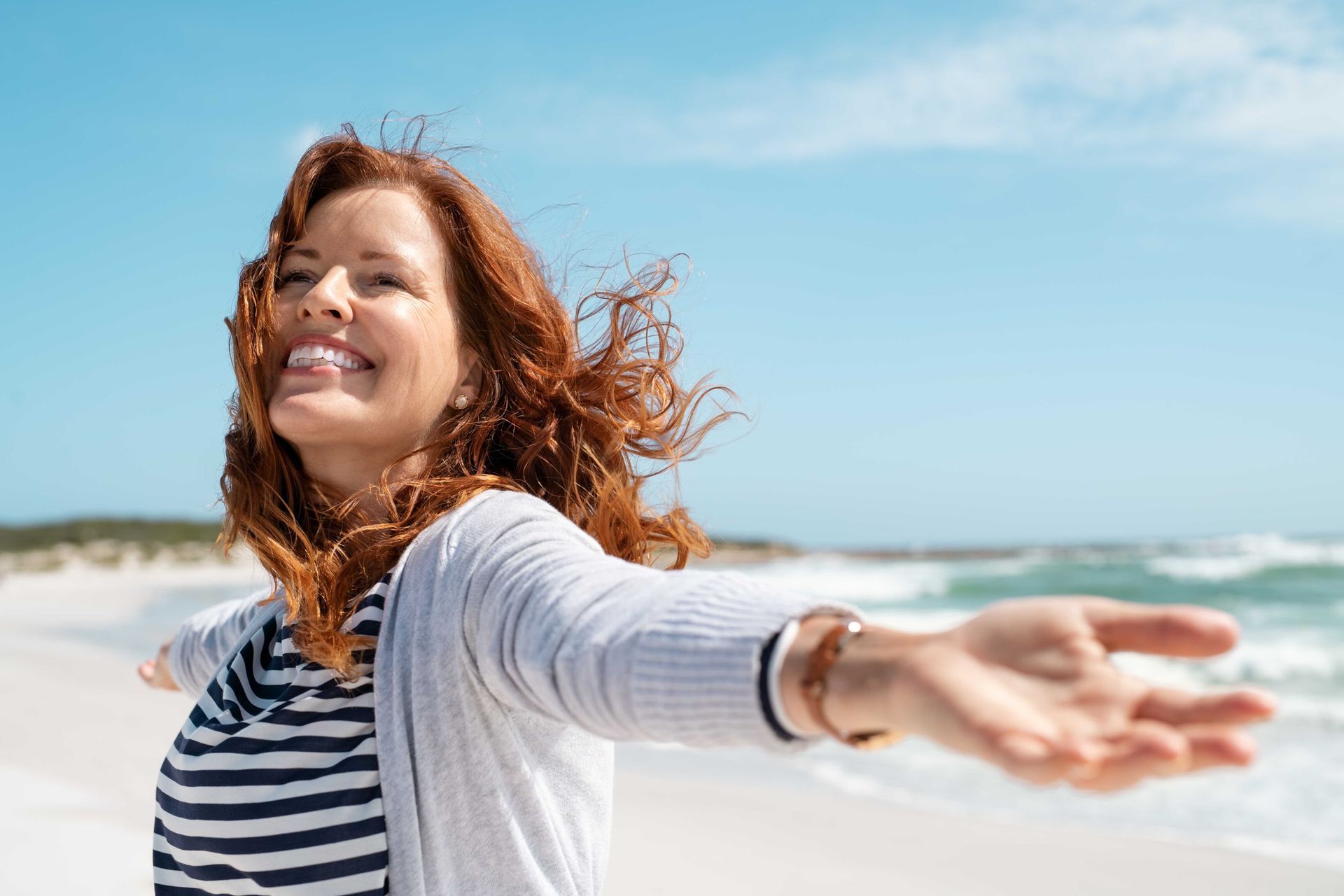 a woman is standing on the beach with her arms outstretched