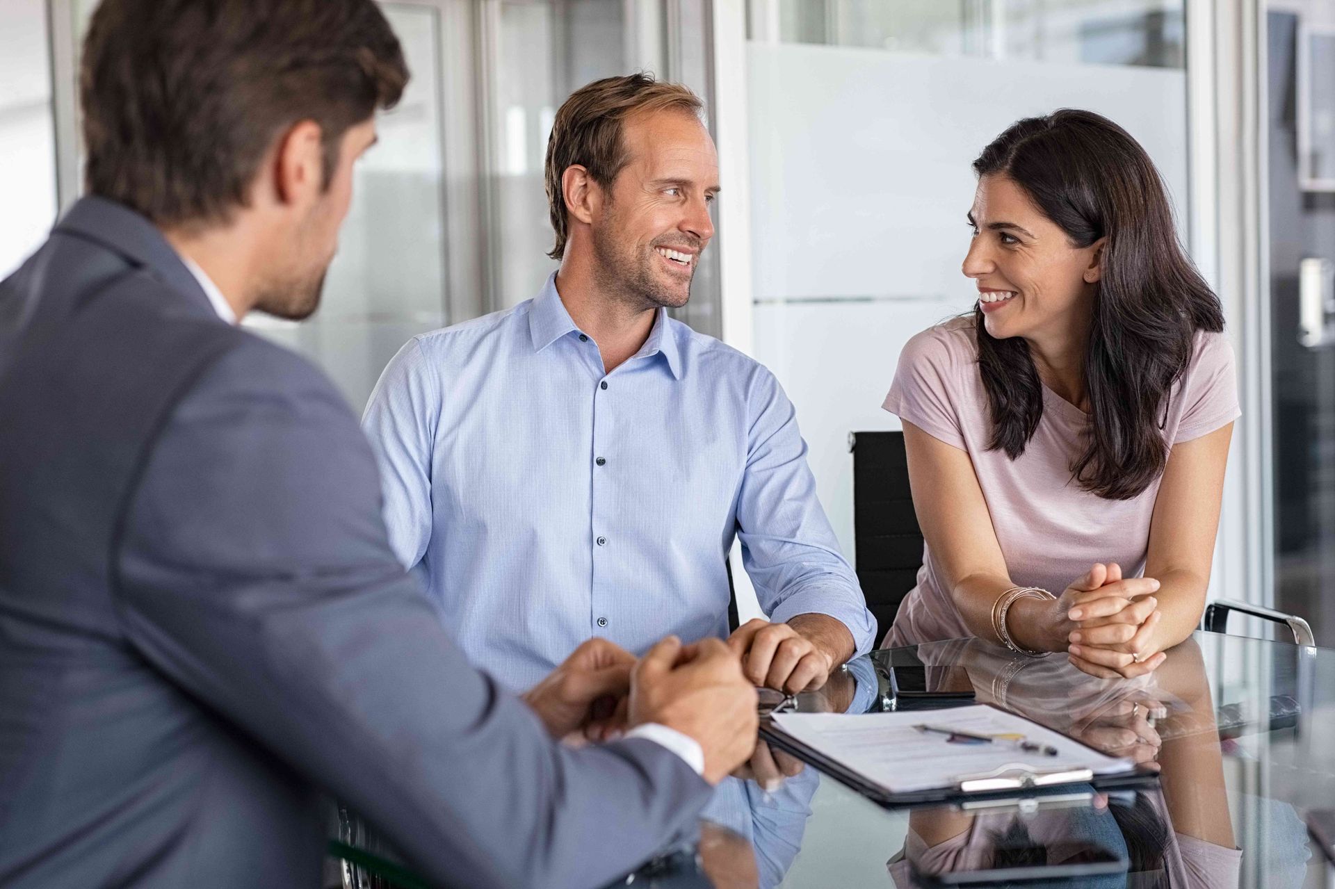a man and a woman are sitting at a table talking to a man in a suit