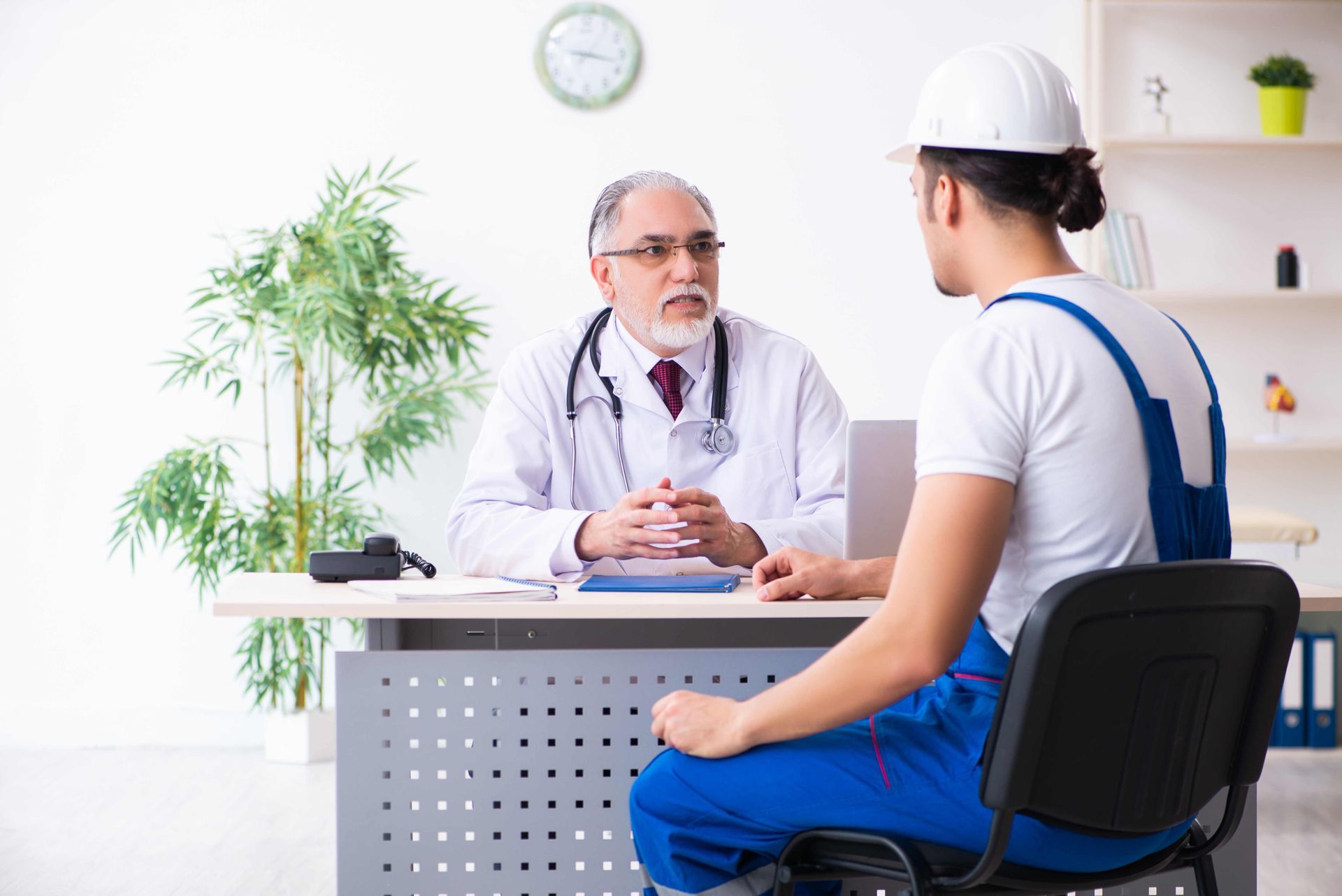 a construction worker is sitting at a desk talking to a doctor