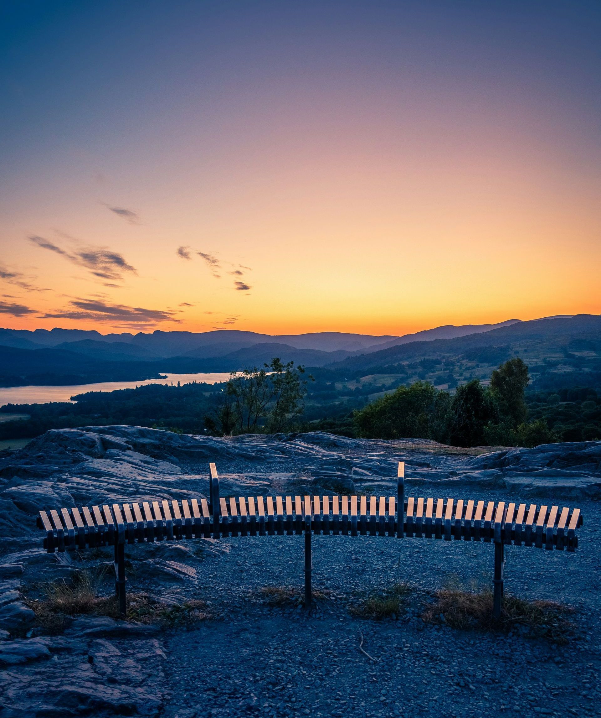 Silhouetted landscape with sunset Top-of-the-mountain perspective looking out on a silhouetted landscape, including a lake, mountains, and a captivating sunset.