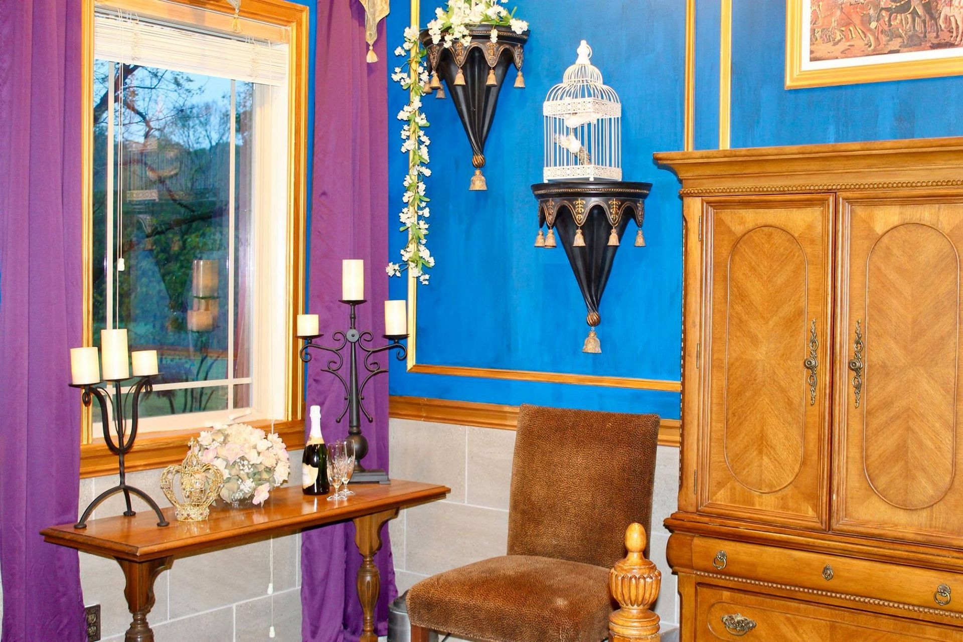 Colorful room with blue and purple walls, mirror, wall decor, small table, and wooden cabinet