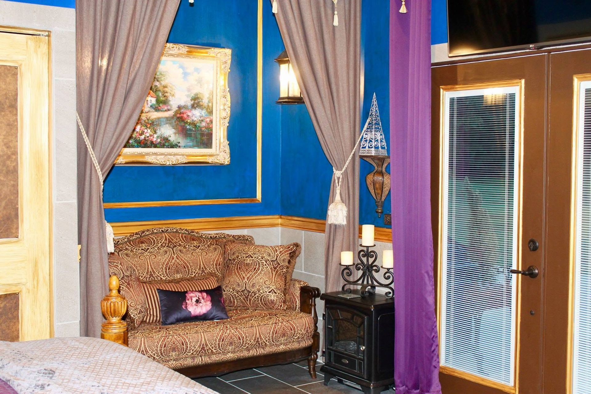 Colorful bedroom with blue walls, gold curtains, patterned sofa, painting, and a mirrored door