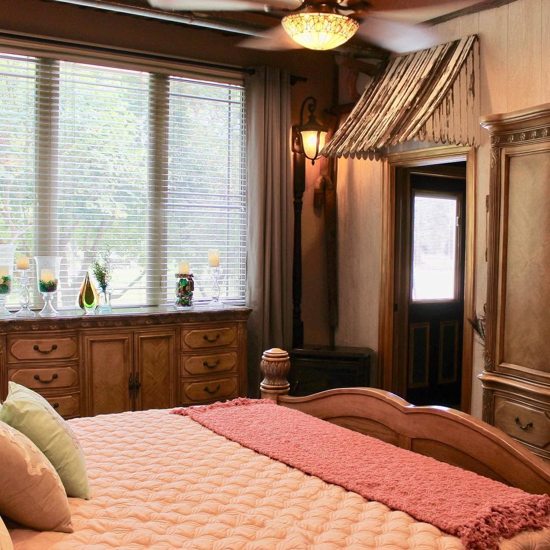 Cozy bedroom with a bed, wooden dresser, window blinds, and warm wood-paneled decor