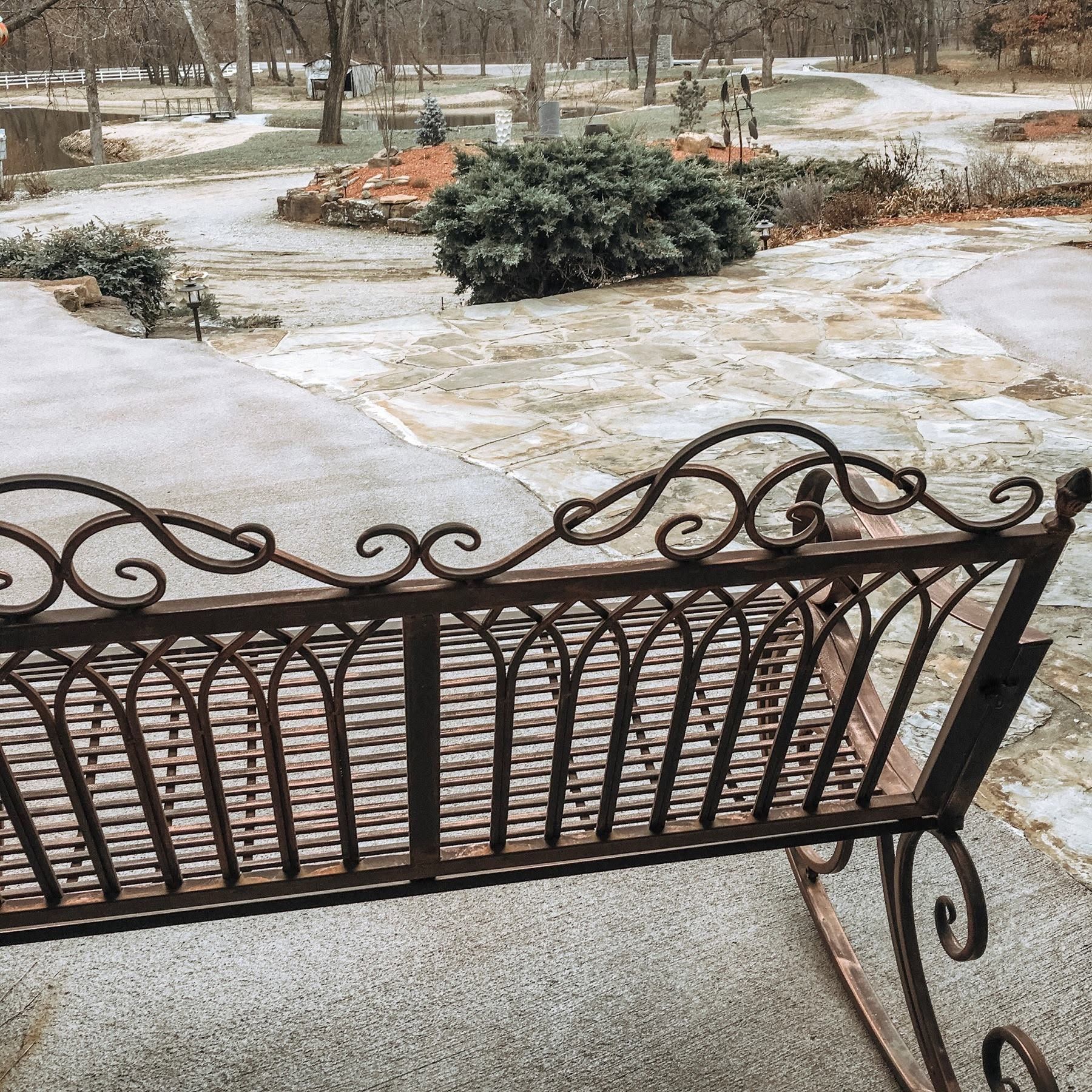 Snow-dusted front yard with a decorative wrought-iron gate and shrubs under an overcast sky