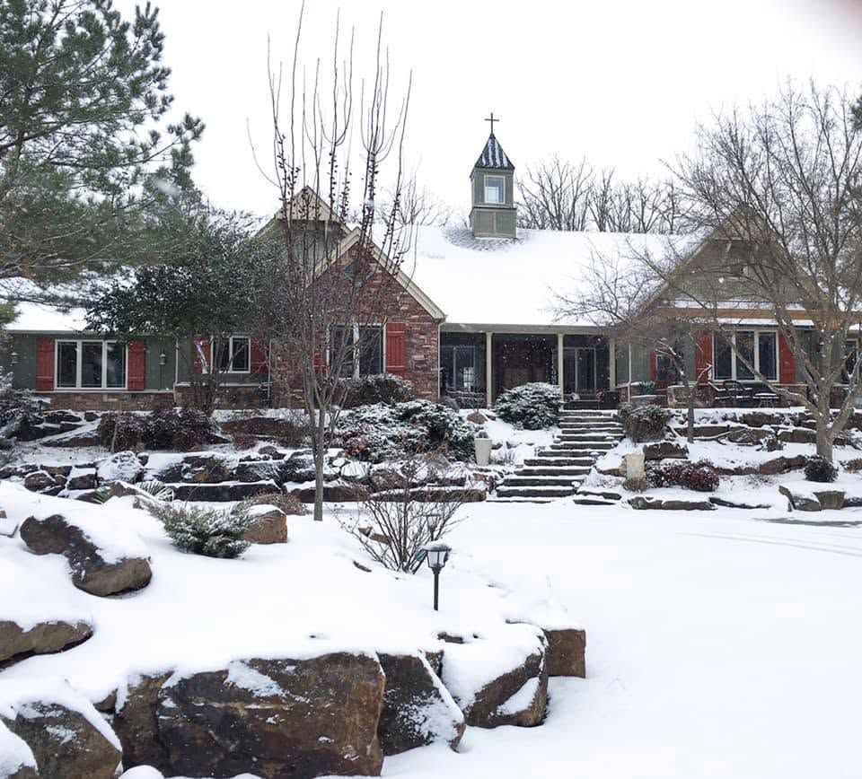 Snow-covered house with a central cupola and stone garden in winter