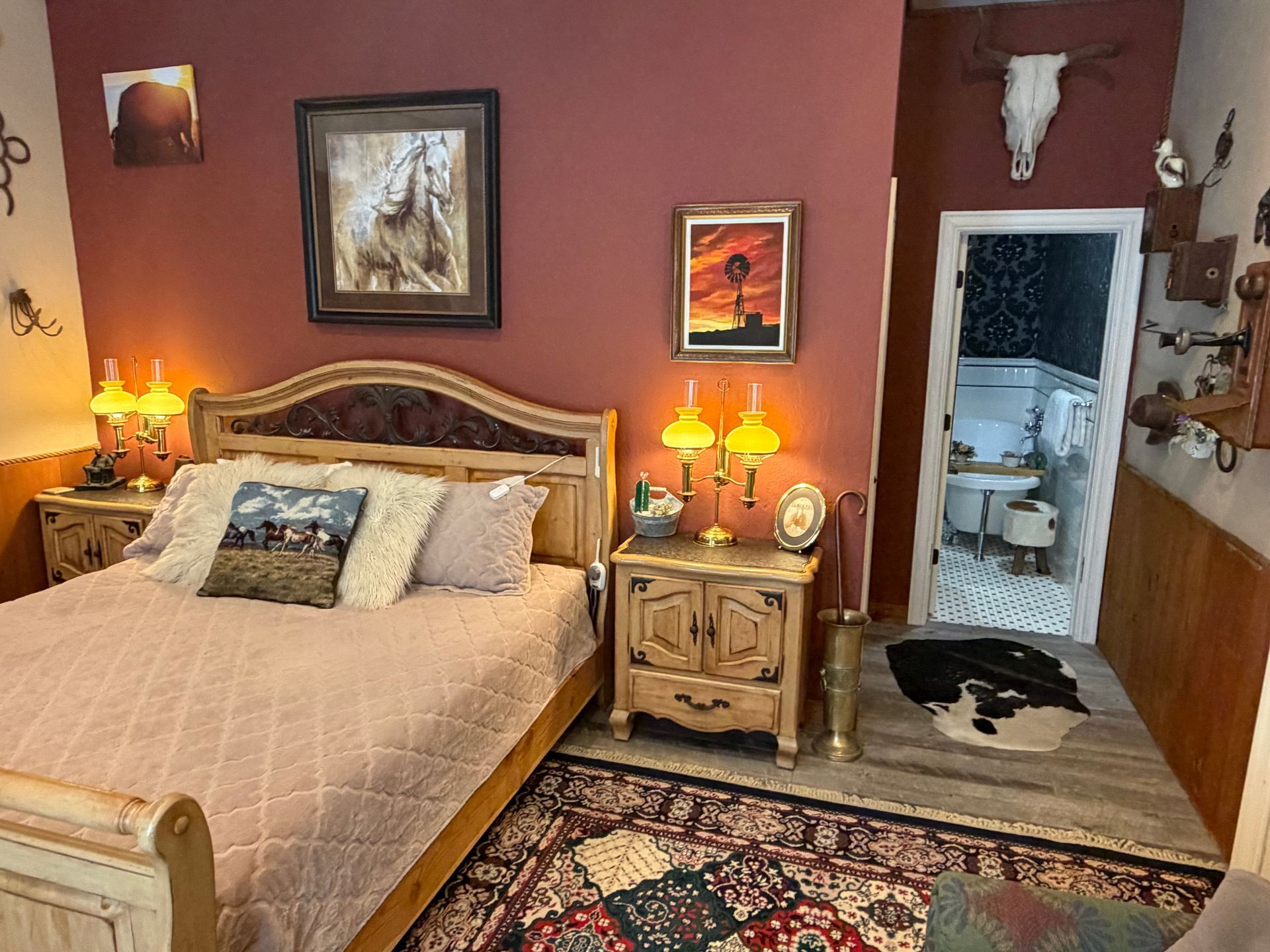 Cozy bedroom with red walls, carved bed, patterned rug, bedside lamp, and open doorway to a snowy patio