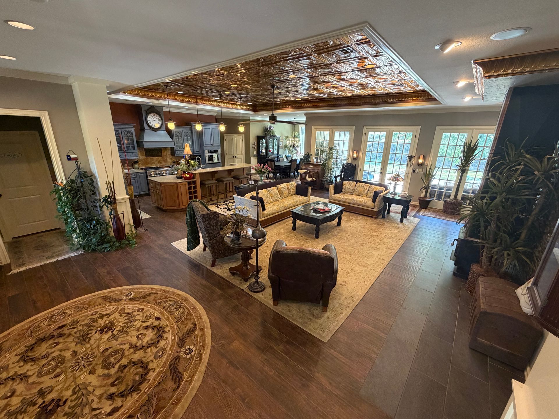 Modern lounge with dark wood floors, patterned rugs, sofas, tables, and glass doors to a bright patio