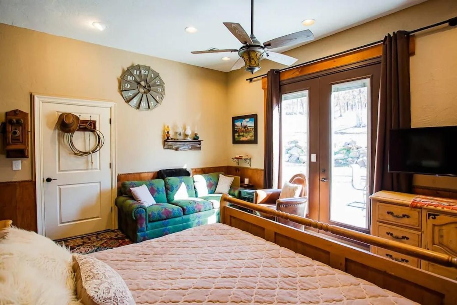 Cozy bedroom with a bed, sofa, wall clock, ceiling fan, and glass doors to a balcony