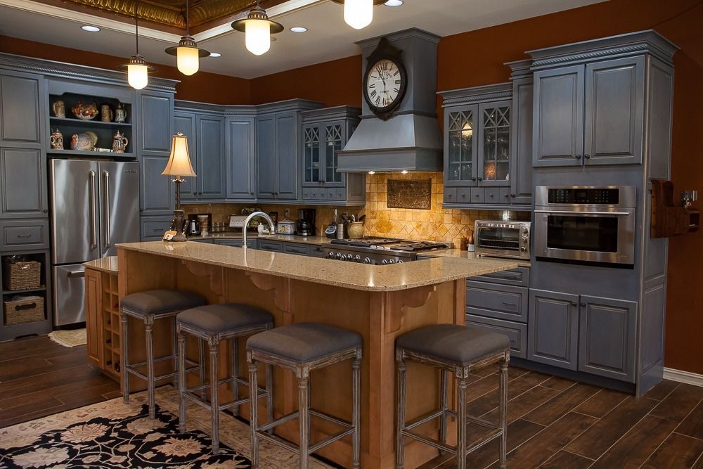 Modern kitchen with blue cabinets, granite island, bar stools, and stainless steel appliances