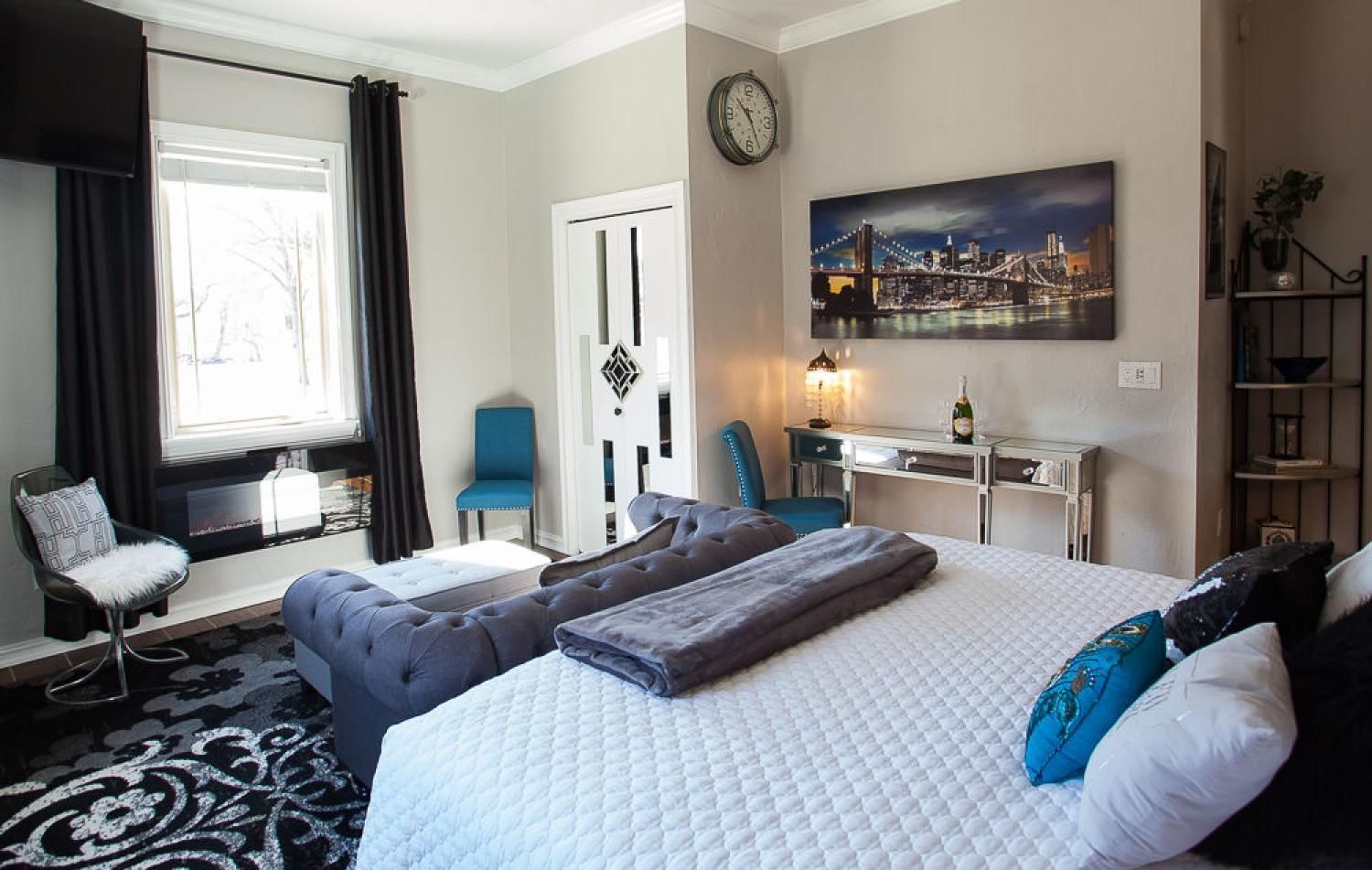 Bright bedroom with a large bed, twin daybed, desk, wall art, and patterned rug.