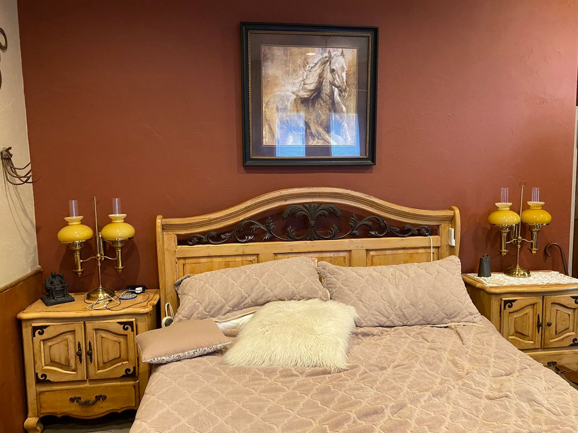Cozy bedroom with a wooden bed, beige bedding, matching nightstands, and warm red walls.