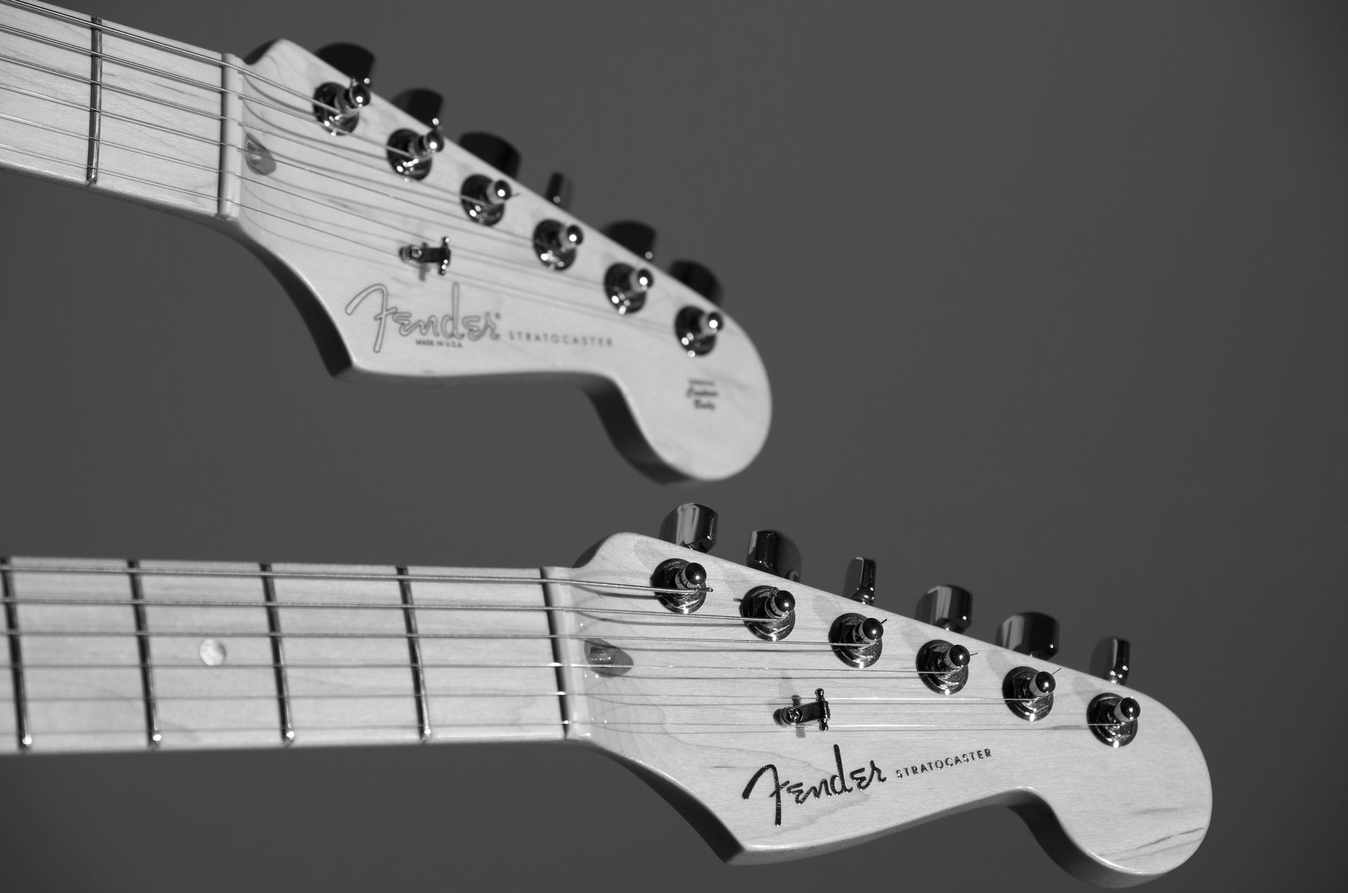 A black and white photo of two fender electric guitars