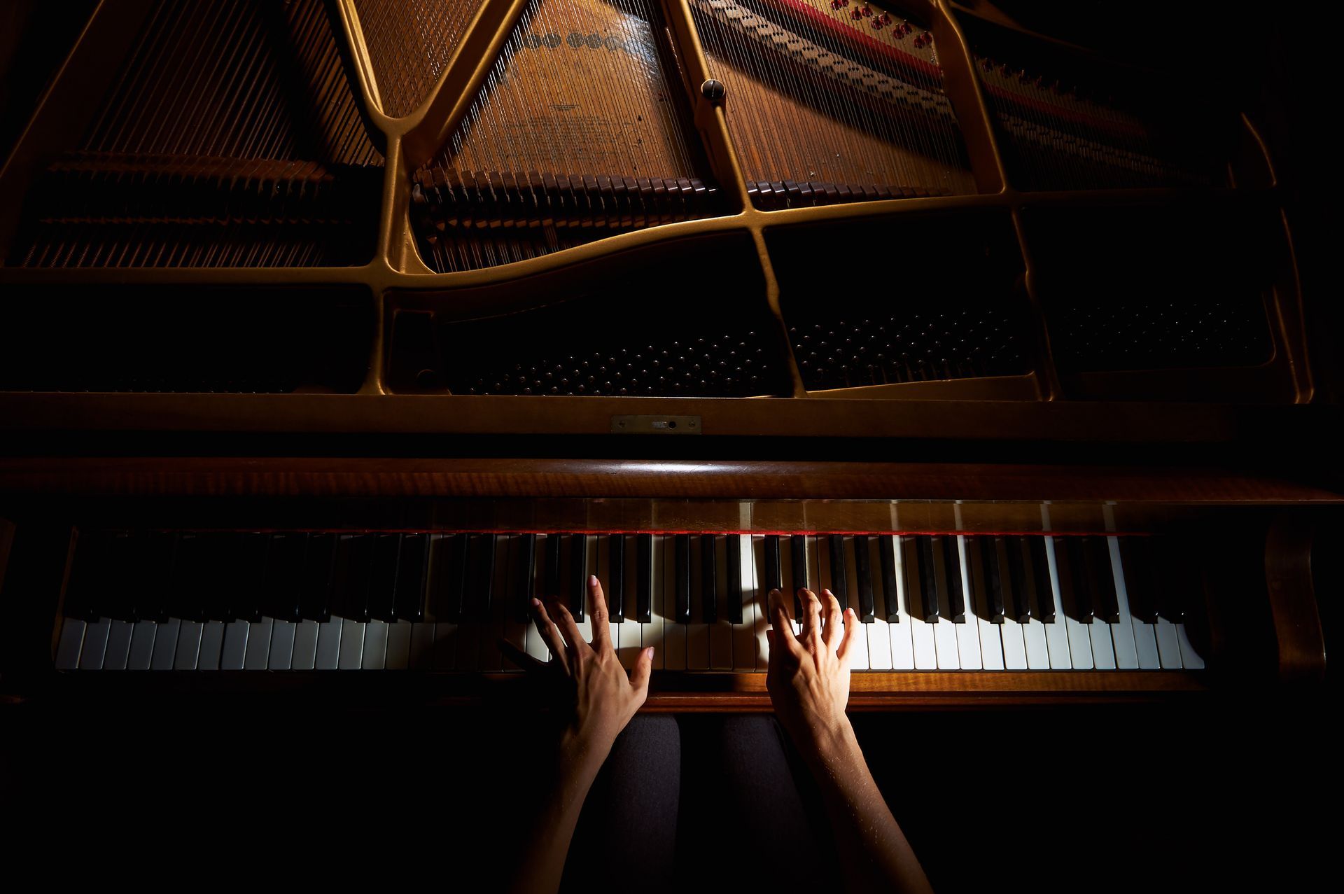 A person is playing a piano in a dark room.