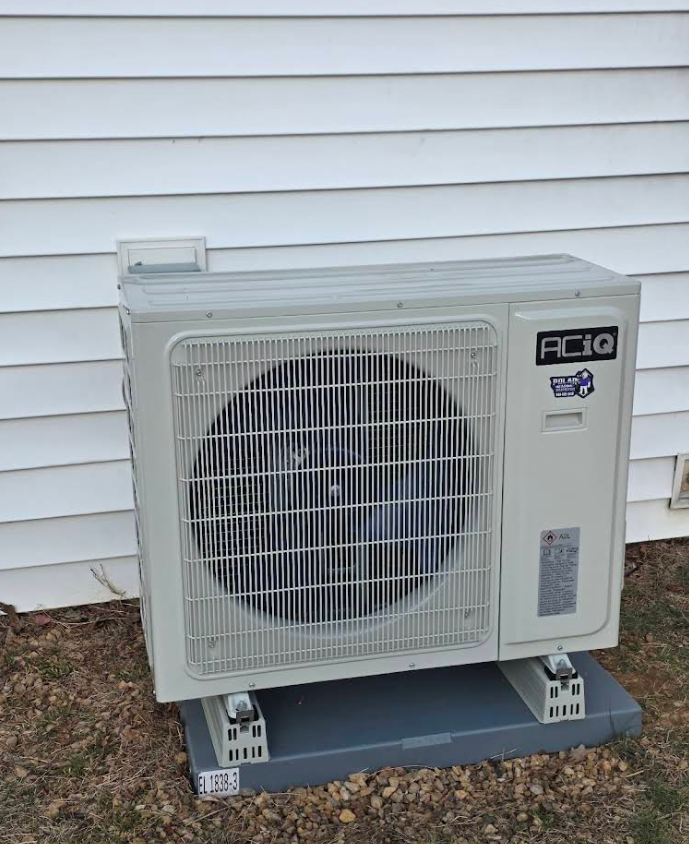 Outdoor AC unit on a concrete pad beside white house siding.