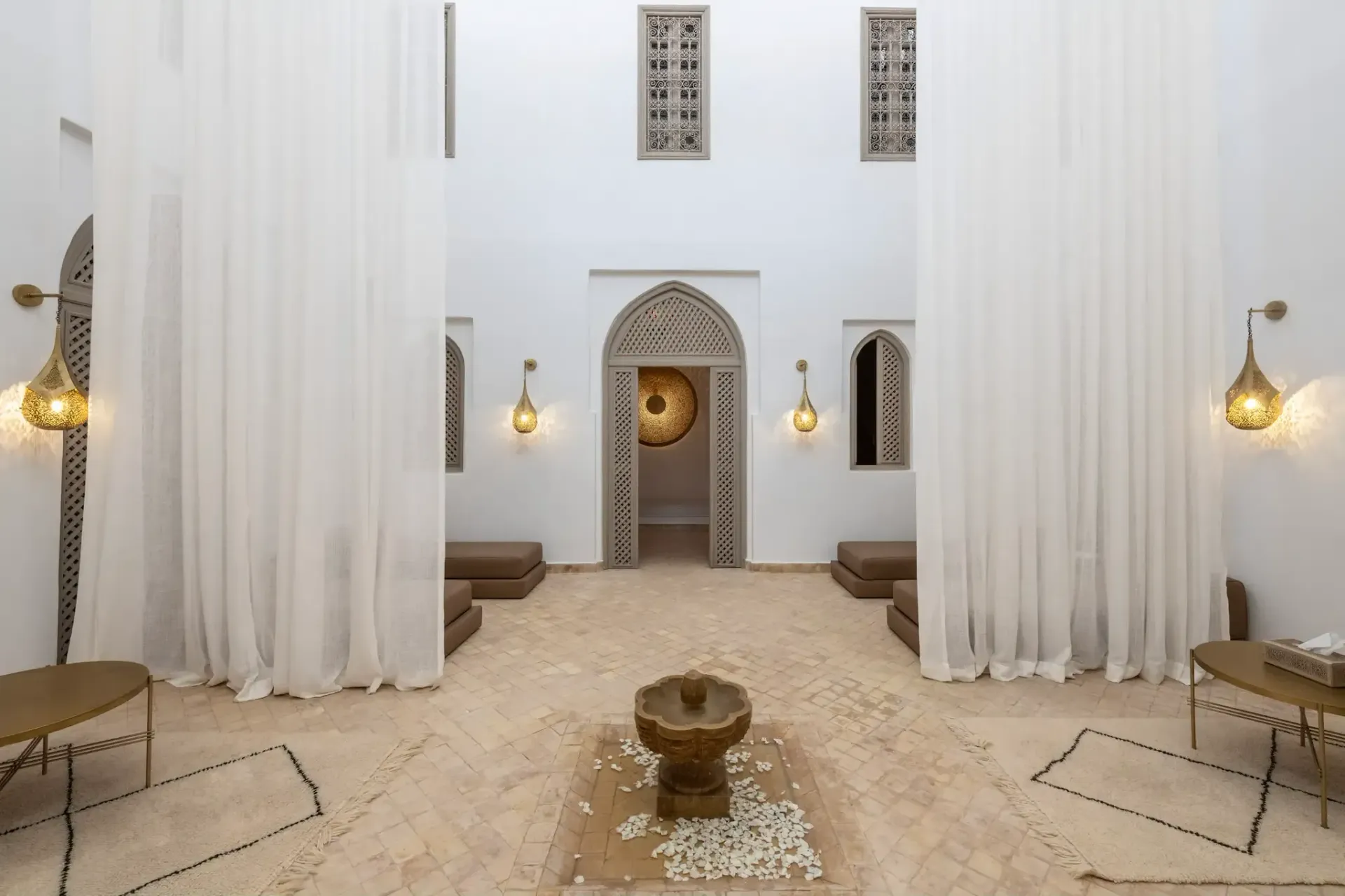 Salle de repos intérieur lumineux de Les Bains de Marrakech avec fontaine et rideaux blancs