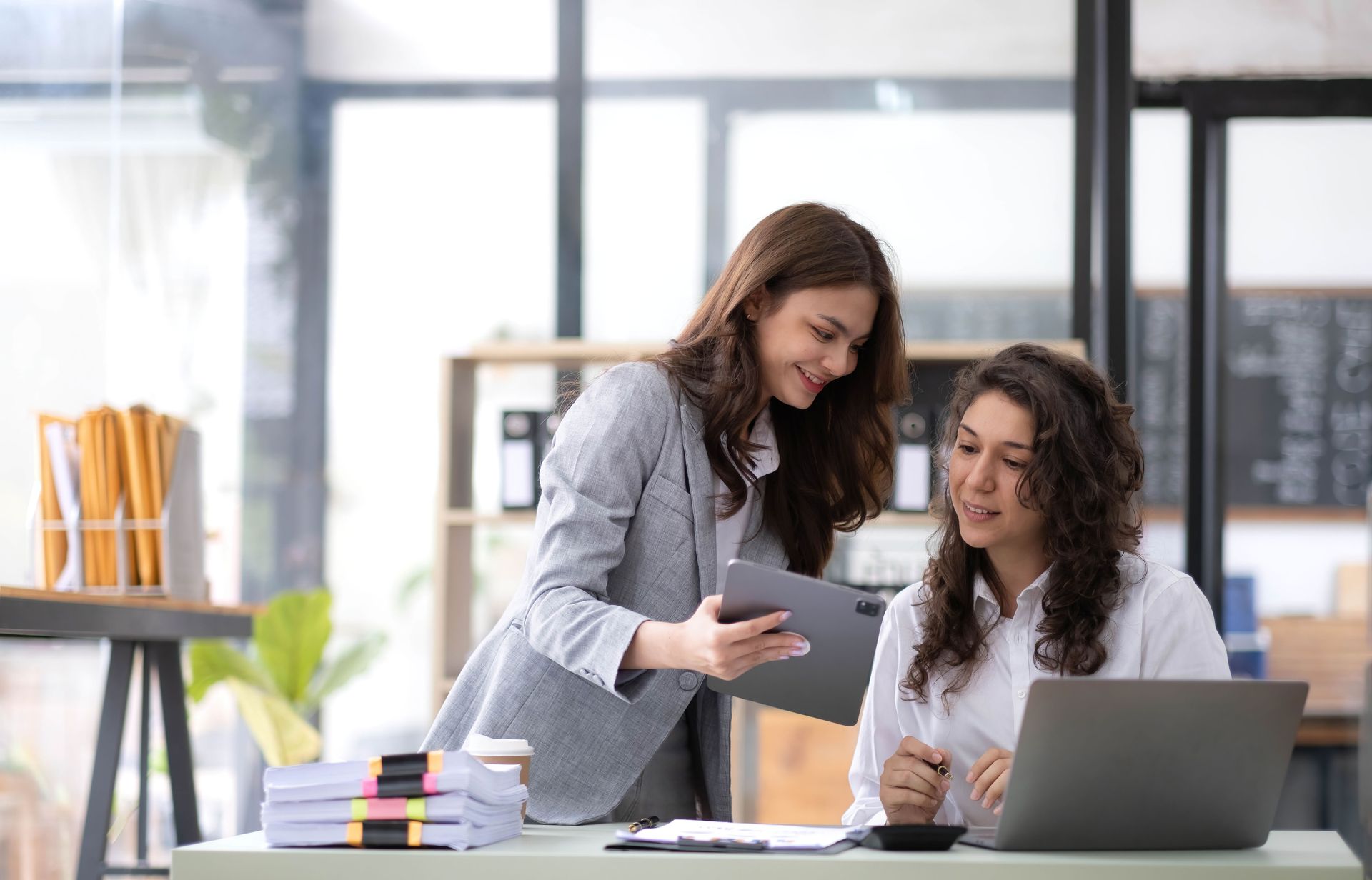 Two women confer at their desks
