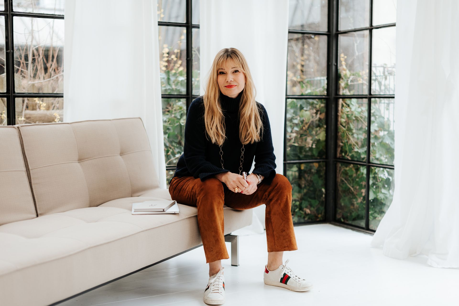 Carolyn Schlak sits on a sofa