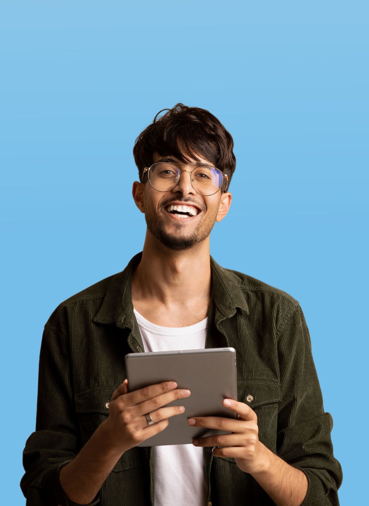 A young man is holding a tablet computer and smiling.