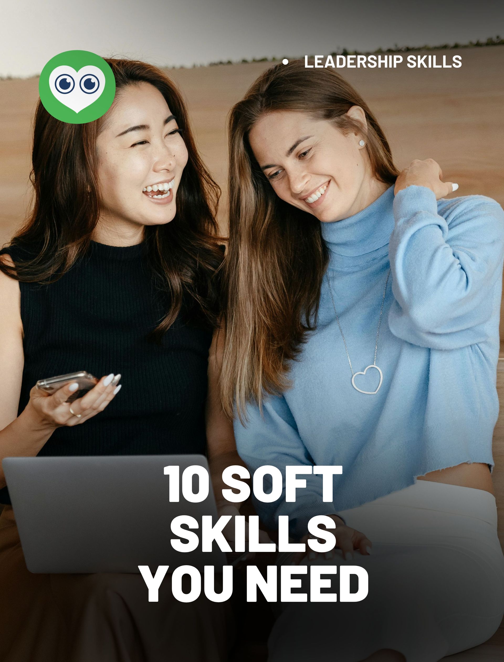 Two women are sitting next to each other with a laptop and a cell phone.