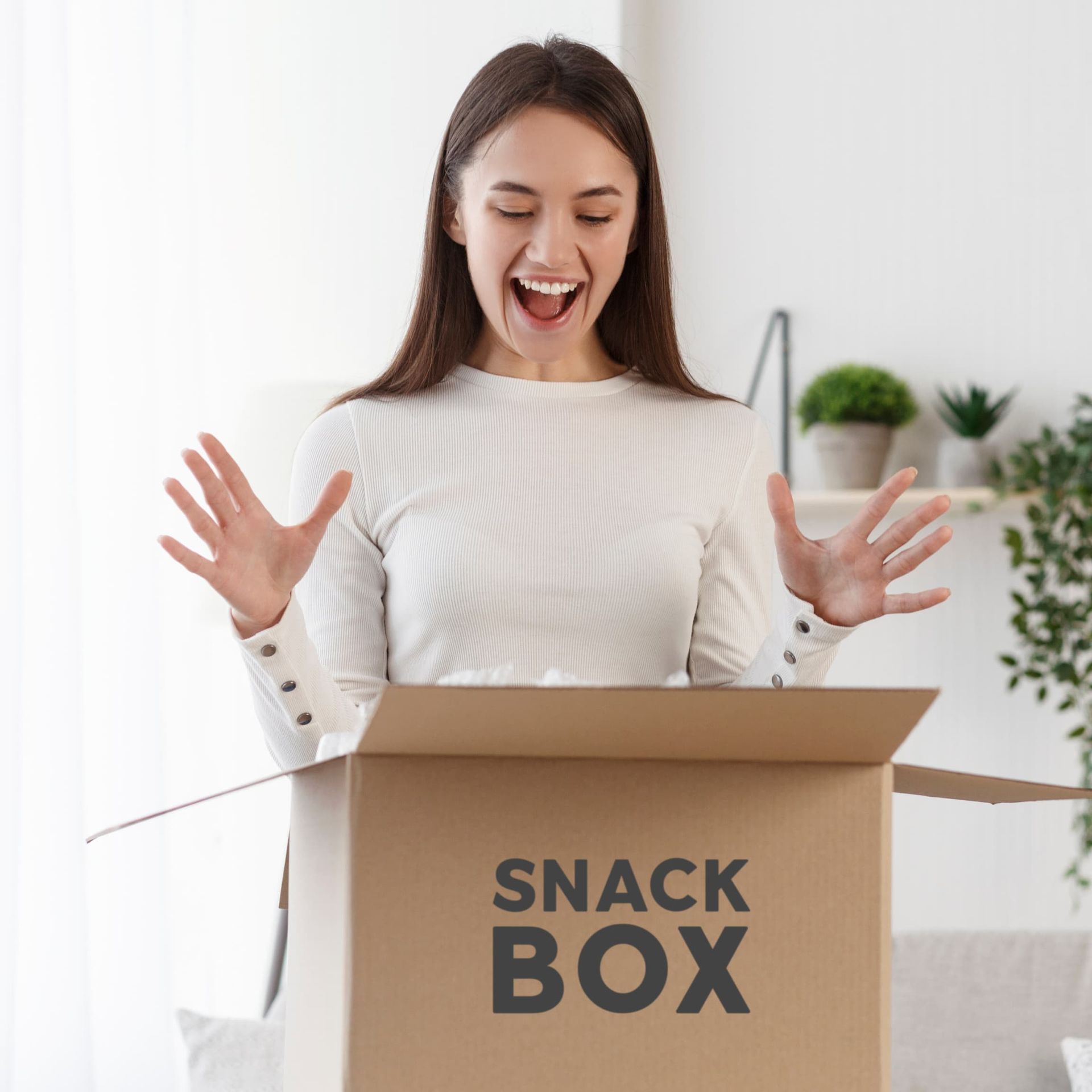 A woman is opening a snack box in a living room.