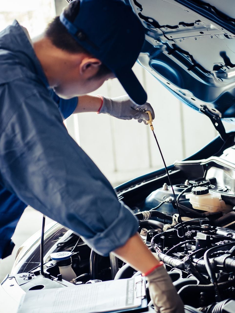 A man is working on the engine of a car with the hood open.