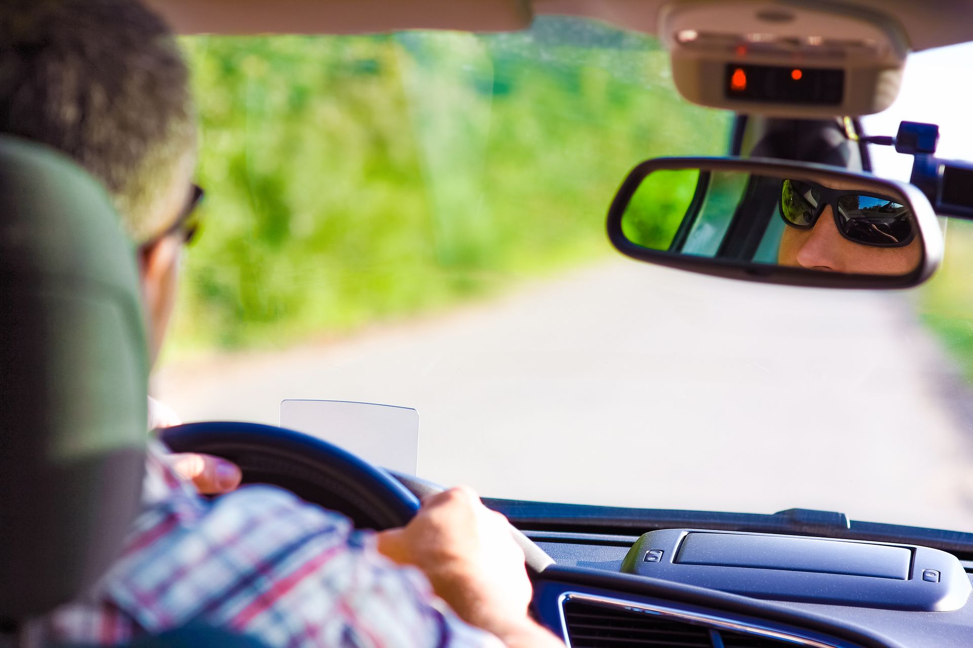 A man is driving a car on a country road.