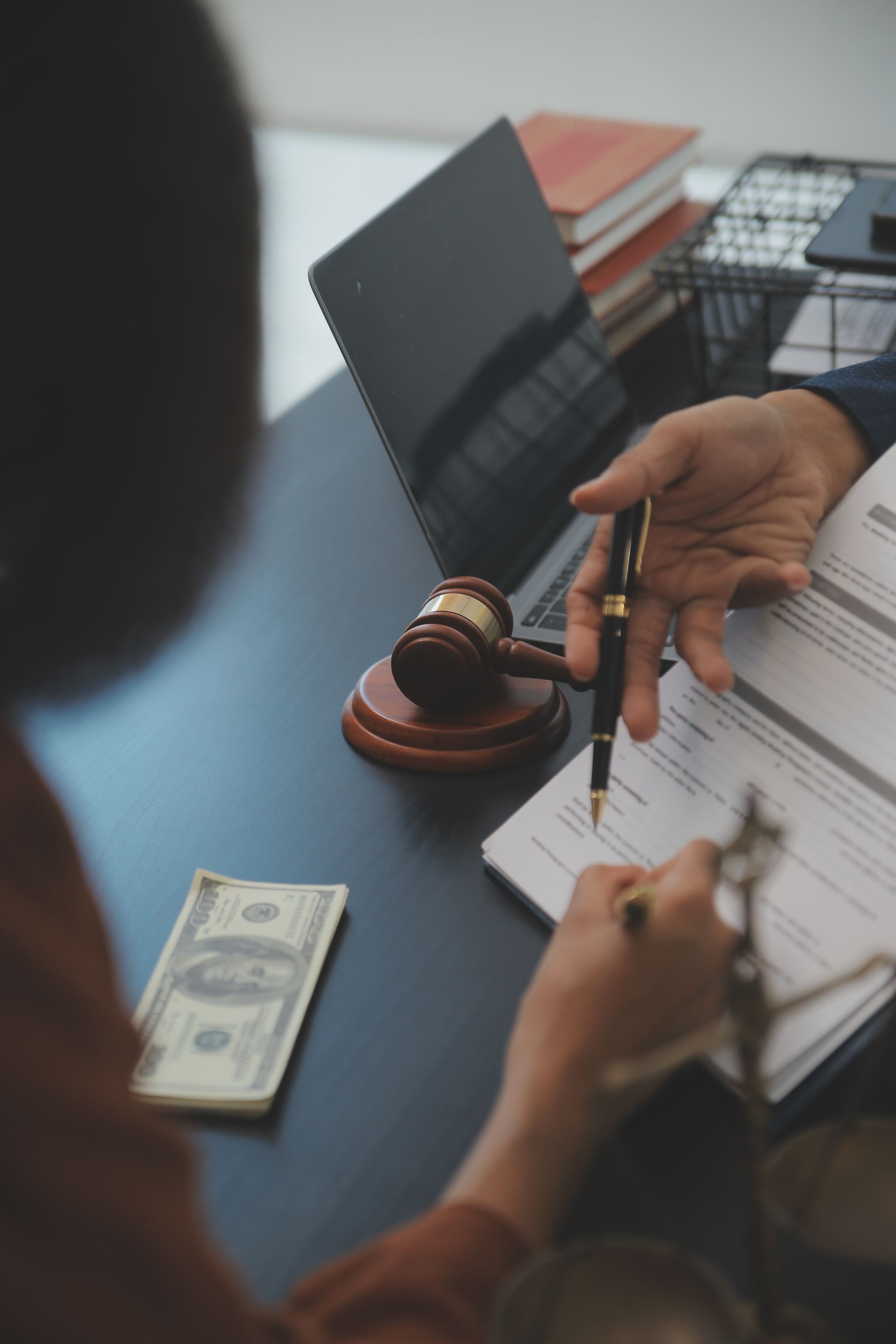 A person is sitting at a desk with a pen and a judge 's gavel.