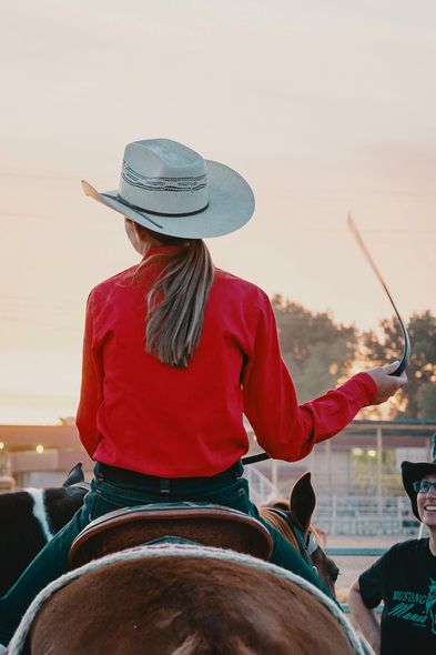 A woman in a cowboy hat is riding a horse.