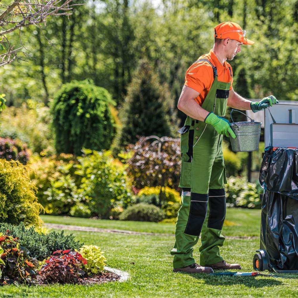 A man is standing in a park holding a bucket.