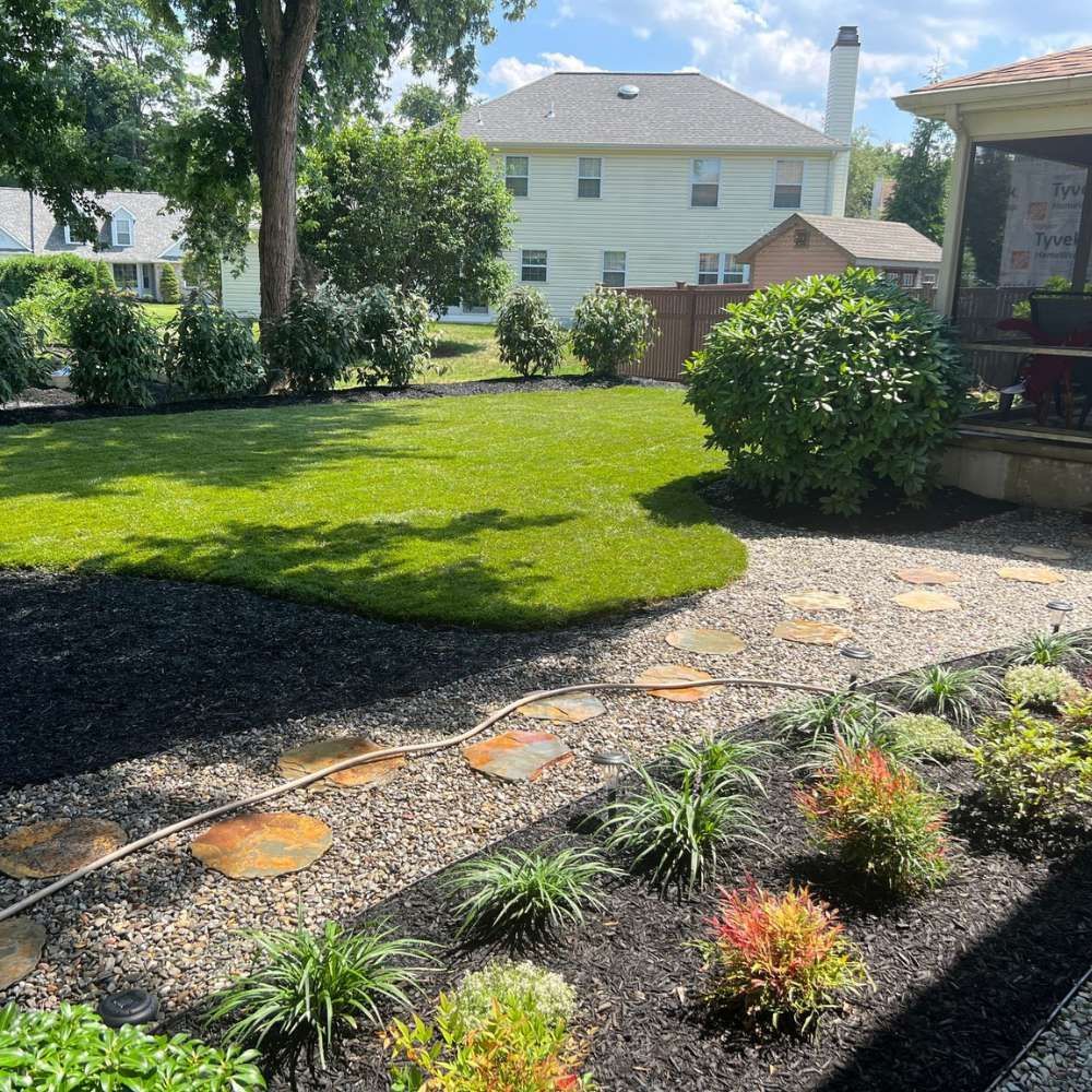 A lush green yard with a stone walkway leading to a house.
