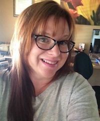 a woman wearing glasses is smiling for the camera while taking a selfie .