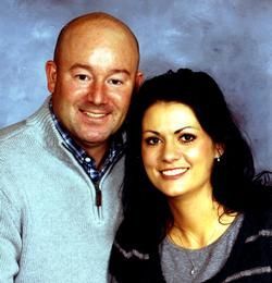 Two smiling people posing closely against a blue studio backdrop