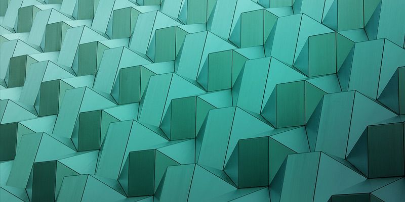 Petrolfarbene geometrisch strukturierte Wand mit gefalteten abstrakten Formen.