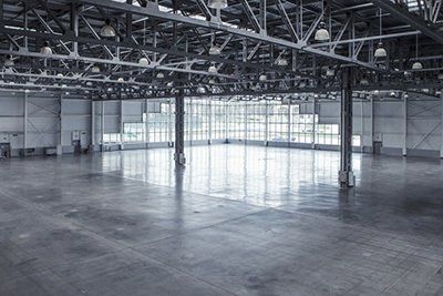 An empty warehouse with a lot of windows and a polished concrete floor.