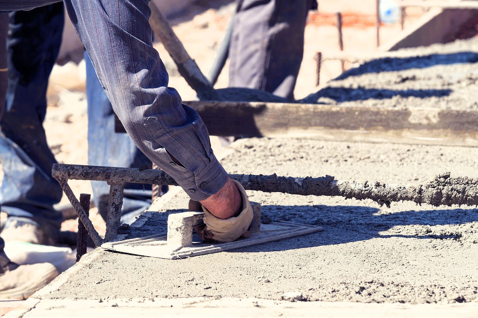 Construction worker leveling outdoor concrete pavement