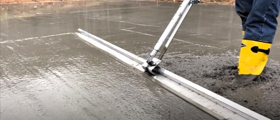Expert is using a float concrete tool to pour concrete on a sidewalk.