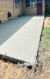A concrete driveway is being built in front of a brick house.