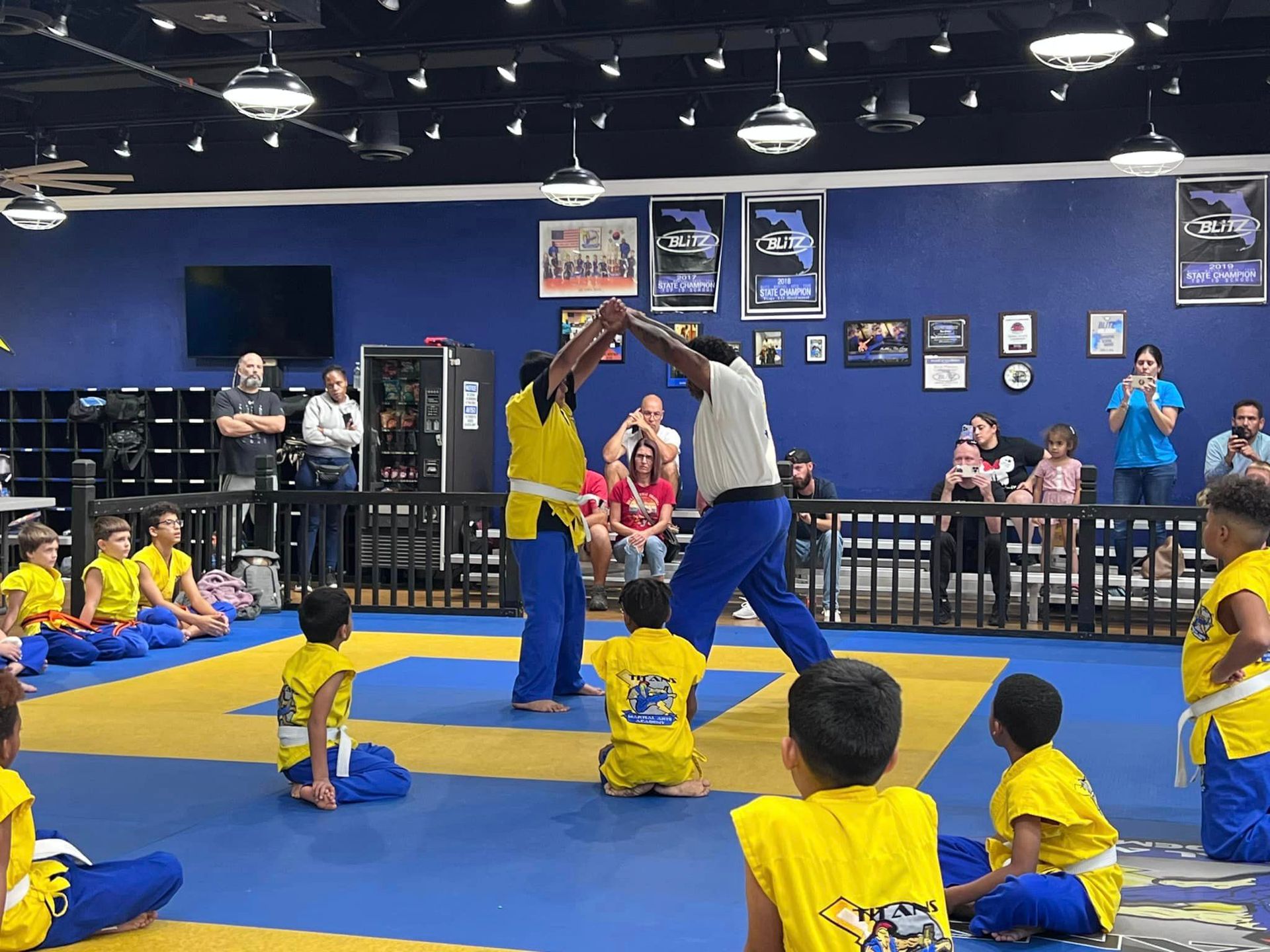 A group of children are practicing martial arts in a gym.