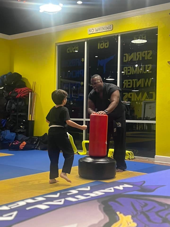 A group of children are doing stretching exercises on a blue and yellow mat in a gym.