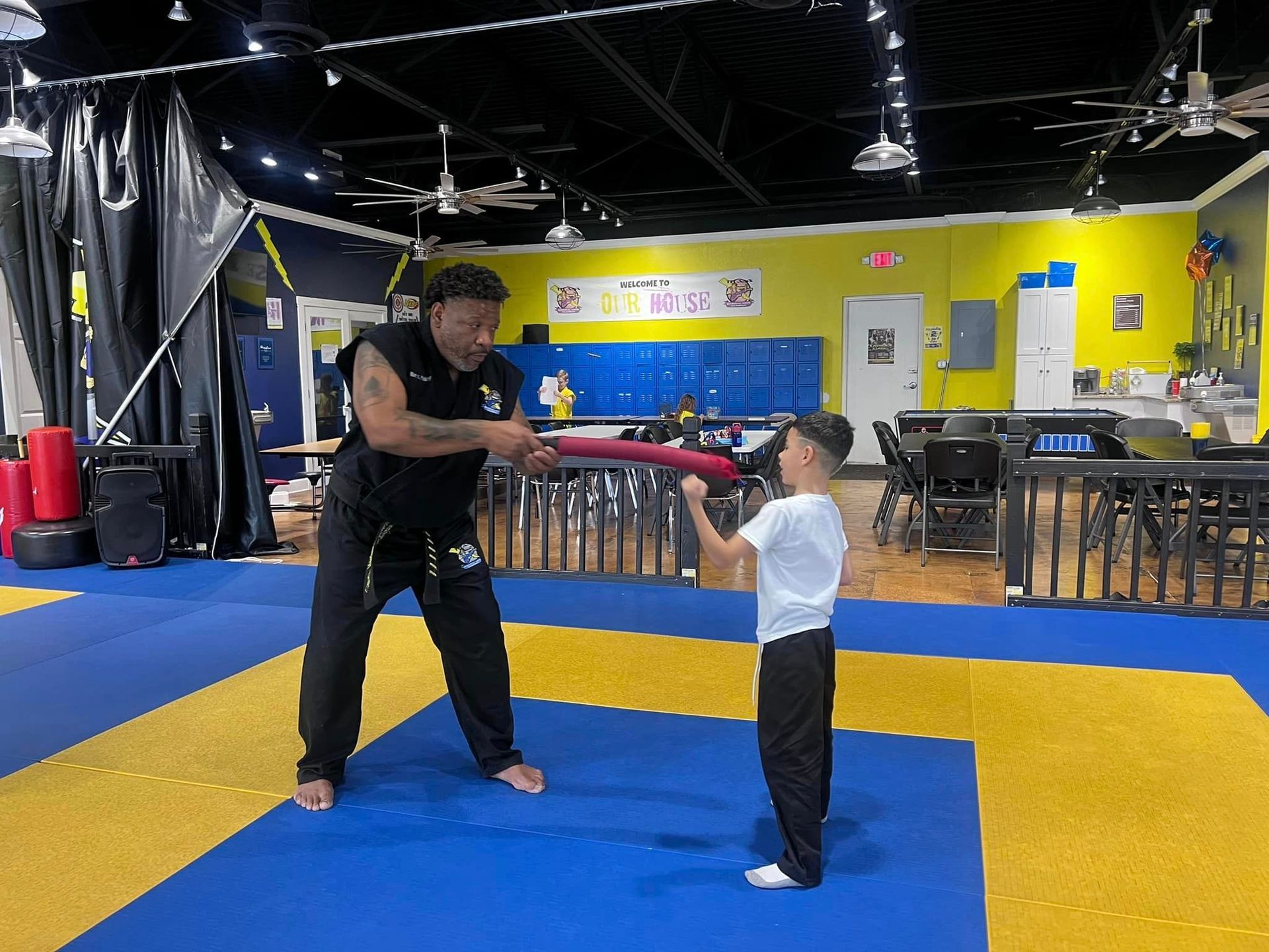 A man and a little boy are practicing martial arts in a gym.