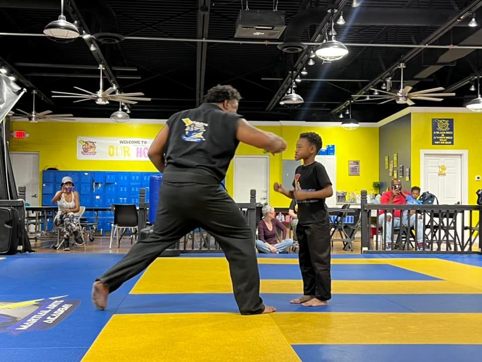 A man and a boy are practicing martial arts in a gym.