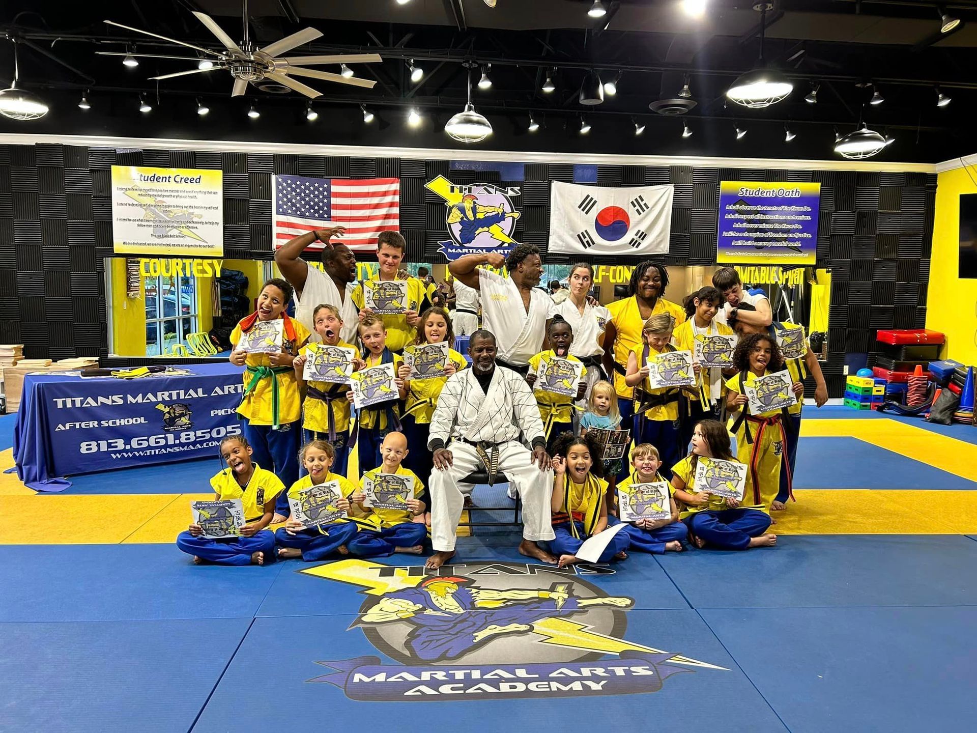 A group of people are posing for a picture in a martial arts academy.