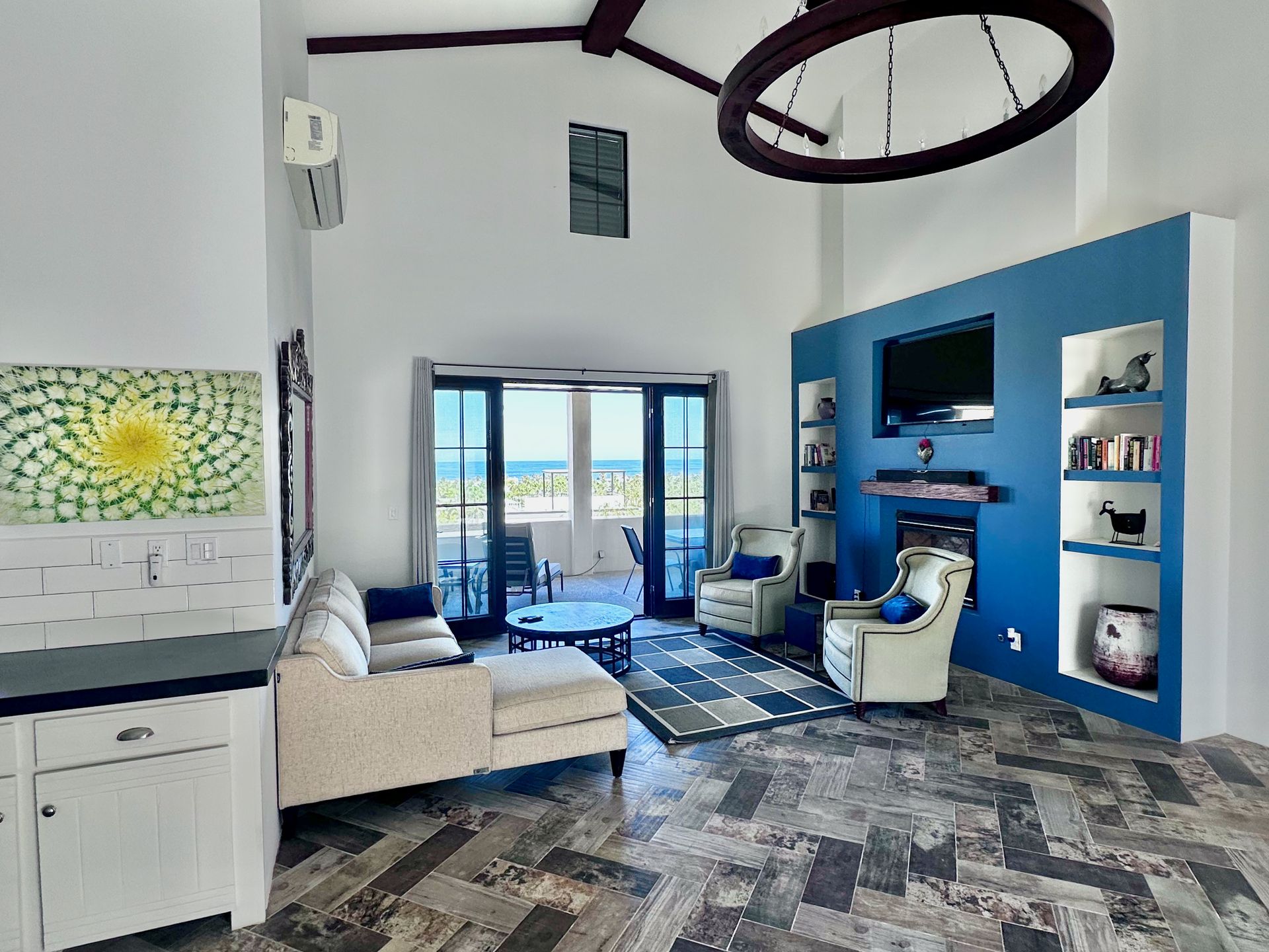 Modern blue-and-white living room with sofa, wall shelves, TV, and balcony doors
