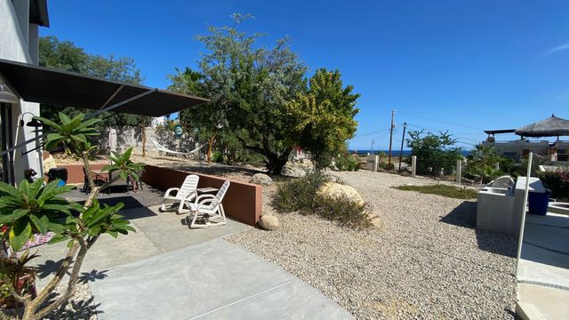 Sunny backyard patio with lounge chairs, gravel landscaping, and umbrella-shaded seating by a house