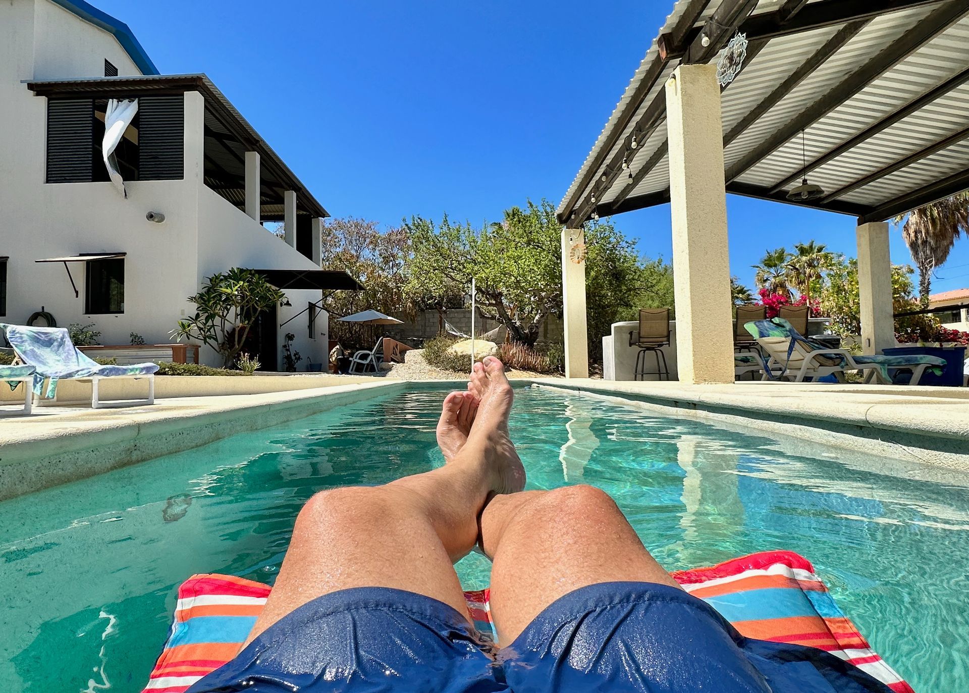 Relaxing by a turquoise pool in a red-striped lounge chair under a bright blue sky