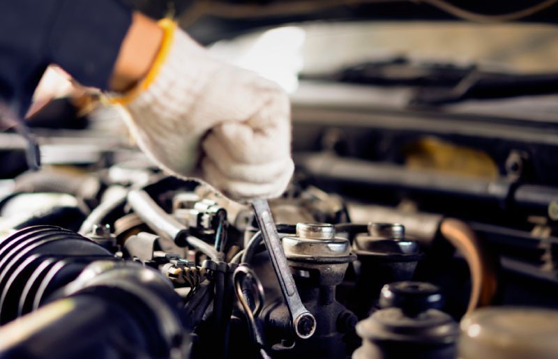 Hands in gloves repairing a four wheel vehicle's engine