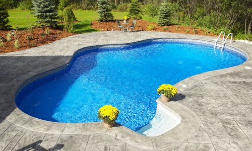 swimming pool with concrete decking surrounding it