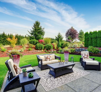 backyard concrete patio area with black furniture .